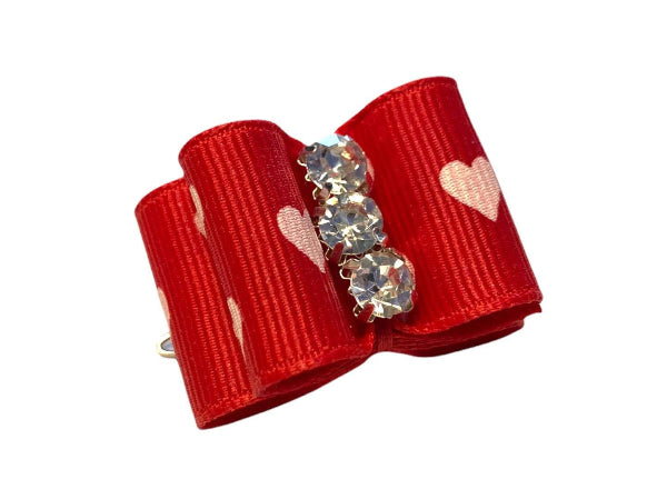 Red bow hair clip with heart and gemstone decorations on a white background