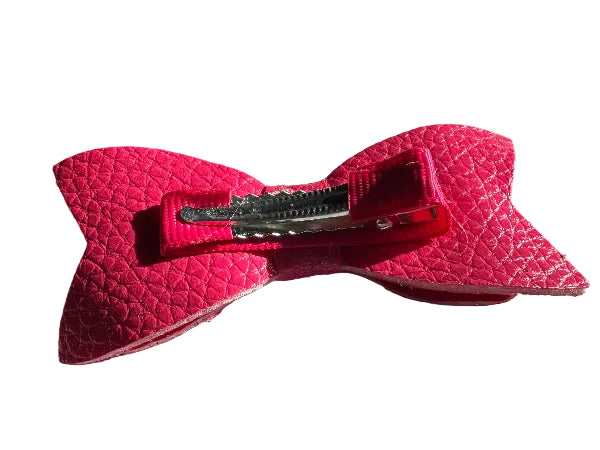 Pink textured bow hair clip on a light gray surface